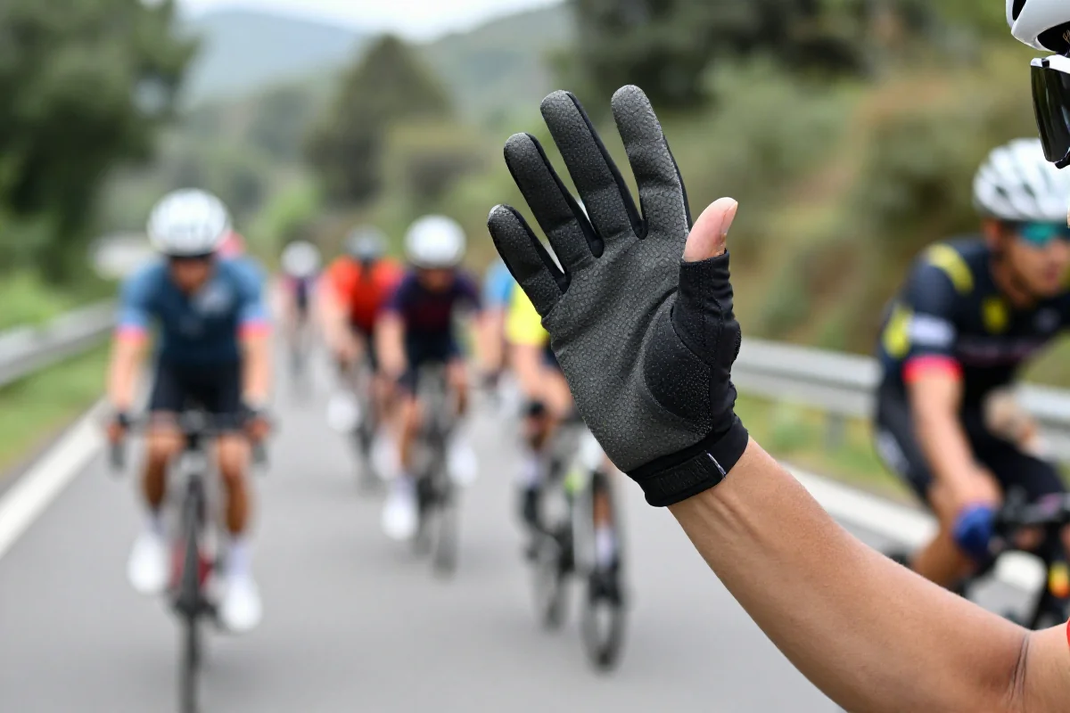 Ręka kolarza sygnalizująca skręt podczas jazdy w grupie.