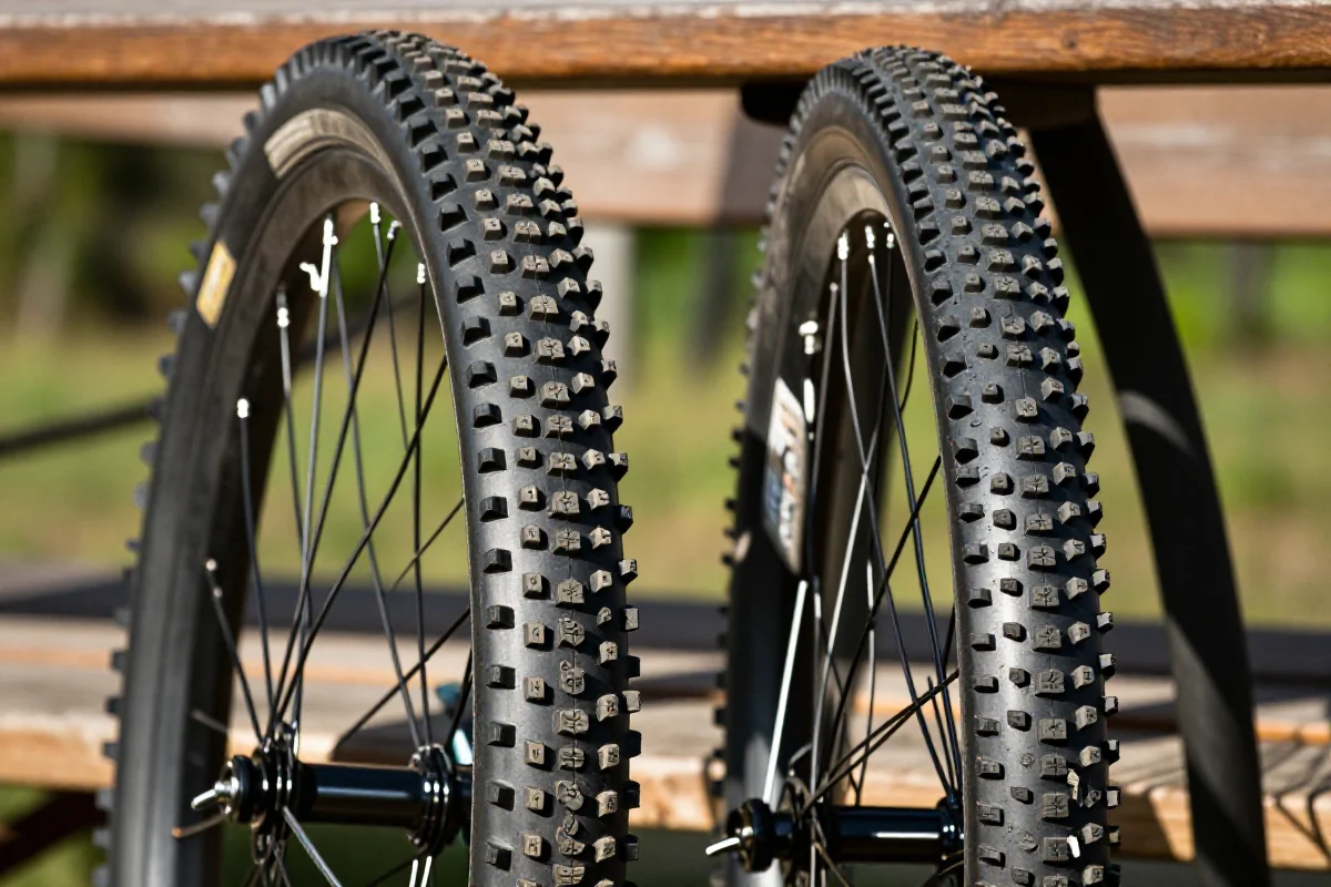 Porównanie opon enduro z agresywnym i uniwersalnym bieżnikiem na tle naturalnym.