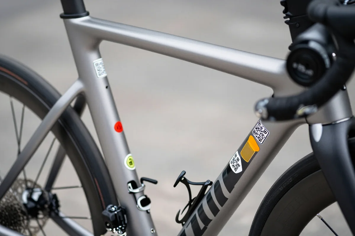 Zbliżenie ramy roweru z naklejkami identyfikacyjnymi na rurze ramy i podsiodłowej.