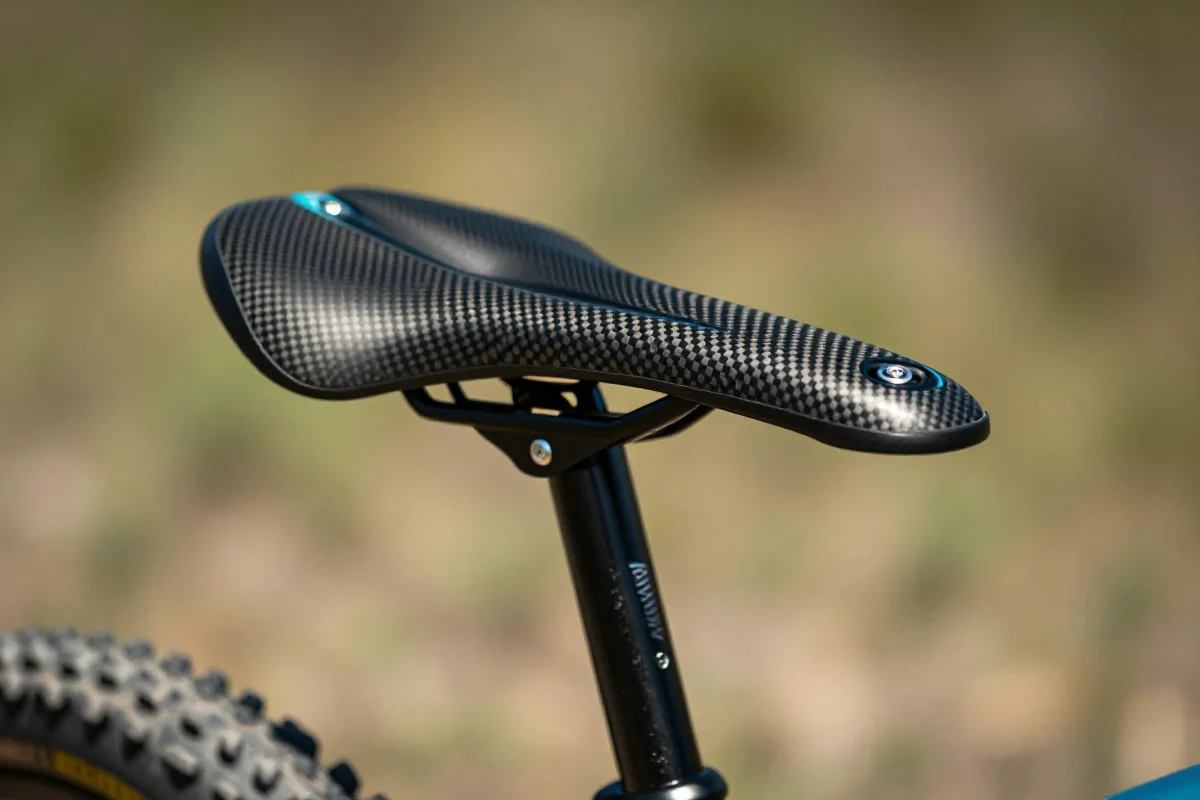 Wąskie siodełko XC MTB z karbonu i tytanu na tle natury
